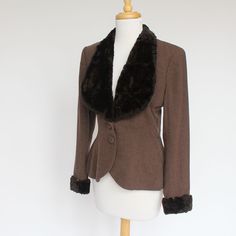 "A long fitted jacket from the 40's with a sheared fur or fleece collar and cuffs. Beautiful vintage styling. Wear it with jeans and boots for a night out or with a skirt and heels to the office. It's a great option for a spring or fall outer jacket. The brown wool jacket is fitted through the waist, has covered buttons, and bound button holes.The brown fur lapels form a lovely collar effect and the cuffs add to the stylish look. The cuffs are snug fitting at the wrist. It is lined with a rust b Retro Formal Winter Outerwear, Retro Tailored Winter Outerwear, Retro Fitted Winter Outerwear, Classic Fitted Blazer With Padded Collar, Vintage Winter Outerwear For Formal Occasions, Fitted Winter Outerwear For Vintage Fashion, Vintage Outerwear For Formal Winter Occasions, Vintage Formal Winter Outerwear, Winter Formal Blazer With Padded Collar