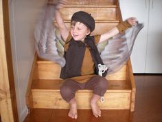 a young boy sitting on top of a wooden step next to an angel wings costume