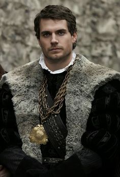 a man dressed in medieval clothing standing next to a stone wall