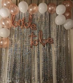 balloons and streamers decorate the backdrop for a bride to be party with rose gold, white and silver confetti