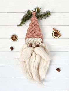 a crocheted santa clause hat on top of a white wooden table next to christmas decorations