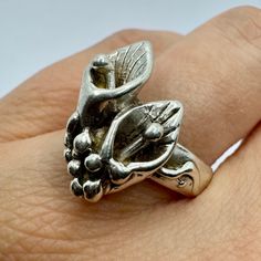 a close up of a person's hand wearing a ring with flowers on it