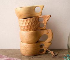 a stack of wooden bowls sitting on top of a table next to a glass bottle