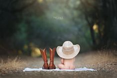 a baby wearing a cowboy hat sitting on top of a blanket next to two boots