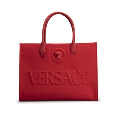 Versace canvas tote bag with embossed logo and Medusa head accent  Rolled top handles  Open top with snap strap closure  Interior, one zip pocket Approx. 11.4"H x 15".8W x 7.5"D "La Medusa" is made in Italy Versace Handbags, Medusa Head, Donatella Versace, Coach Horse And Carriage Tote, Monogrammed Items, Gianni Versace, Open Top, Embossed Logo, Canvas Tote Bag