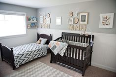 a baby's room with two cribs and pictures hanging on the wall