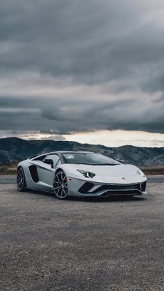 a white sports car parked in an empty parking lot with mountains in the back ground