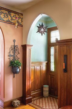 an entryway with wood paneling and arched doorways, potted plant on the door