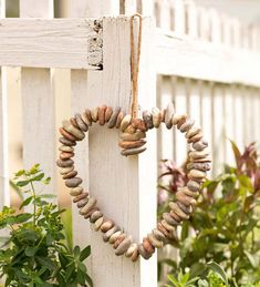 a heart shaped wreath hanging on the side of a white picket fence