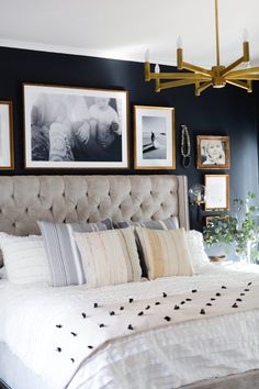 a bedroom with black walls and pictures on the wall above the bed, along with framed photos