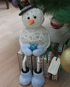 a snowman sitting on top of a box next to a christmas tree