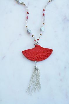 a red necklace with beads and tassels on a marble surface, featuring an intricate design