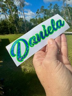 someone holding up a sticker with the word dorkleba in blue and green