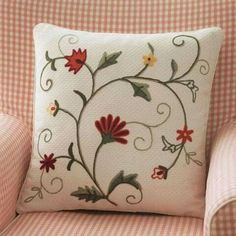 a white pillow with red and yellow flowers on it sitting on a checkered chair