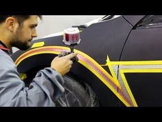 a man is working on a car with yellow tape and red light in the background