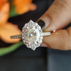 a woman's hand holding an engagement ring with a diamond in the center and two rows of diamonds on each band