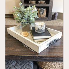 a wooden tray with two books and a candle on it sitting on top of a table