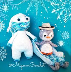 two crocheted stuffed animals are sitting next to each other in front of snowflakes