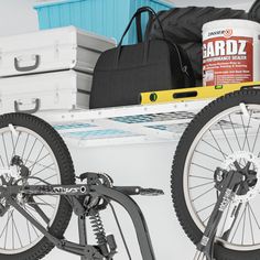 two bikes are parked next to each other in a garage with tools on the shelf