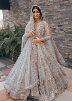 a woman in a white and gold bridal gown posing for the camera with her hands on her hips