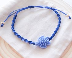 Embrace the spirit of the sea with this Ceramic Turtle Bracelet - a symbol of serenity, strength, and style all in one stunning piece of jewelry. Handcrafted with love and care, this unique bracelet is the perfect addition to your accessory collection. 🐢 Artistry in Ceramic: Our turtle centerpiece is meticulously handcrafted from high-quality ceramic, showcasing intricate detailing and a gorgeous colors. The turtle, a symbol of patience and wisdom, adds a touch of nature-inspired elegance to your outfit. 🌿 Natural Elegance: The braided band of this bracelet complements the turtle beautifully with its earthy tones and texture. The combination of the turtle and the high-quality braided design makes this bracelet an ideal accessory for both casual and formal occasions. 🌎 Eco-Friendly: We c Ceramic Turtle, Ocean Inspired Jewelry, Turtle Bracelet, Braid Designs, Bracelet Blue, Sliding Knot, Unique Bracelets, Ocean Inspiration, Handmade Bracelet