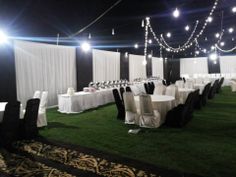 tables and chairs are set up with white linens, black sashes, and lights