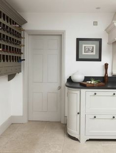 an image of a kitchen with white cabinets and black counter tops that has wine bottles on it