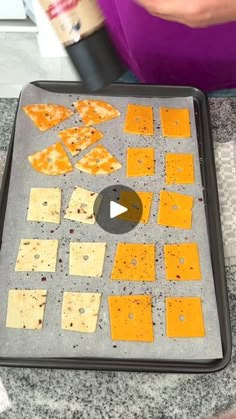 someone is making crackers and cheese on a tray