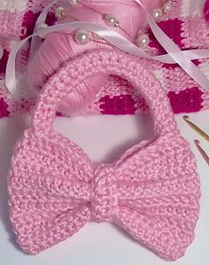 a pink crocheted bow tie next to a pair of scissors