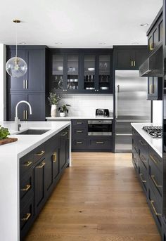 a modern kitchen with black cabinets and white counter tops, gold pulls on the handles