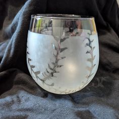 a close up of a wine glass on a black cloth with the reflection of people in it