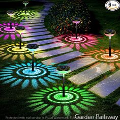 an array of colorful lights on the ground in front of a garden path with grass and flowers