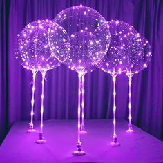 three lighted balloons sitting on top of a purple tablecloth covered in stars and sparkles