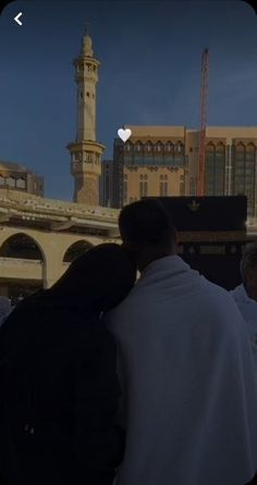 people are standing in front of a building with a clock tower behind them and an apple logo on the screen