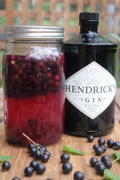 a jar filled with liquid sitting on top of a wooden table next to blackberries