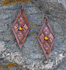 "Stamped leather earrings in a diamond shape, accented with copper paint. A Swarovski crystal in the center adds just a touch of sparkle.  2 ¼\" long by 1 1/8\" wide." Elegant Hand Tooled Brown Jewelry, Elegant Hand-tooled Brown Jewelry, Handmade Rust Leather Jewelry, Elegant Brown Soldered Jewelry, Brown Leather Jewelry With Soldered Details, Painted Leather Earrings, Copper Paint, Stamped Leather, Earrings Diamond