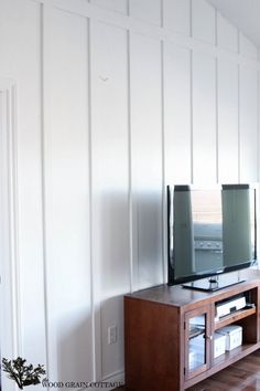 a flat screen tv sitting on top of a wooden entertainment center in a living room