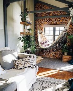 a living room filled with furniture and a hammock hanging from the ceiling in front of a window