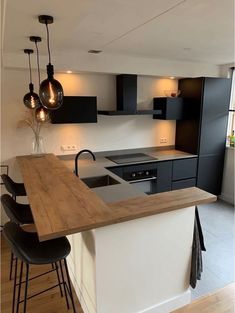 a kitchen with black and white cabinets, an island countertop and bar stools