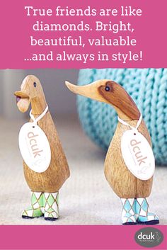 two wooden ducks are standing next to each other, one has a tag on its neck