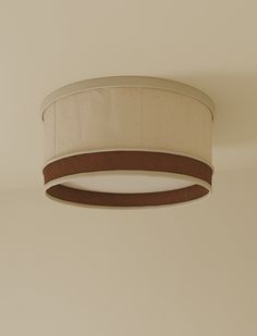 a round light fixture hanging from the ceiling in a room with beige walls and flooring