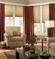 a living room with two couches and chairs in front of large windows that have red drapes on them