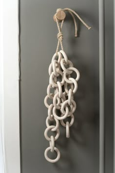 a white chain hanging from the side of a door next to a hook on a gray wall