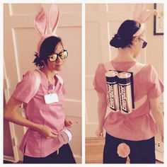 a woman in bunny ears and pink shirt with candy bar on her back, standing next to a door