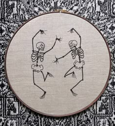 a cross stitch pattern with two skeletons dancing