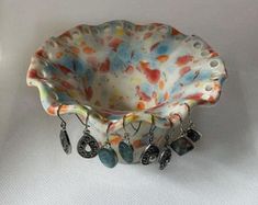 a ceramic bowl with earrings hanging from it