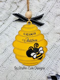 a yellow christmas ornament with a bee on it's side and the words, i'll be home for christmas