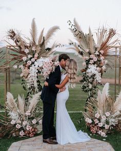 a bride and groom kissing under an arch decorated with flowers