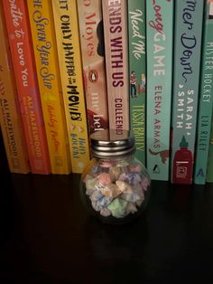 a glass jar filled with lots of candy sitting on top of a table next to books