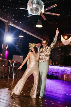 a man and woman dancing on the dance floor at a wedding in front of a disco ball